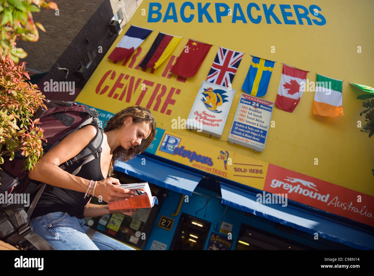 Junge Frau lesen Ratgeber außerhalb ein Backpacker-Hostel. Kings Cross, Sydney, New South Wales, Australien Stockfoto