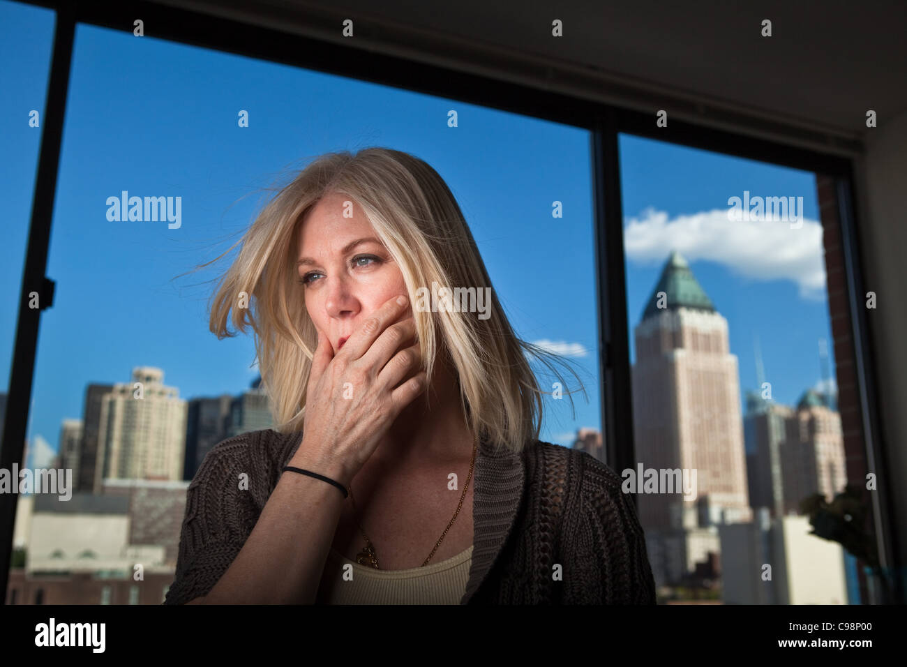 Reife Frau sucht ängstlich Büro mit Stadtbild sichtbar hinter Stockfoto