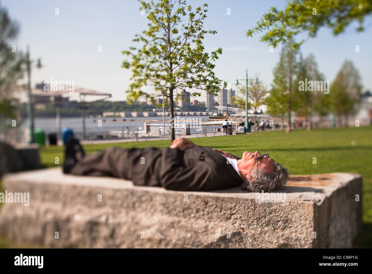 Ältere Mann liegend auf Stein Block Park Stockfoto