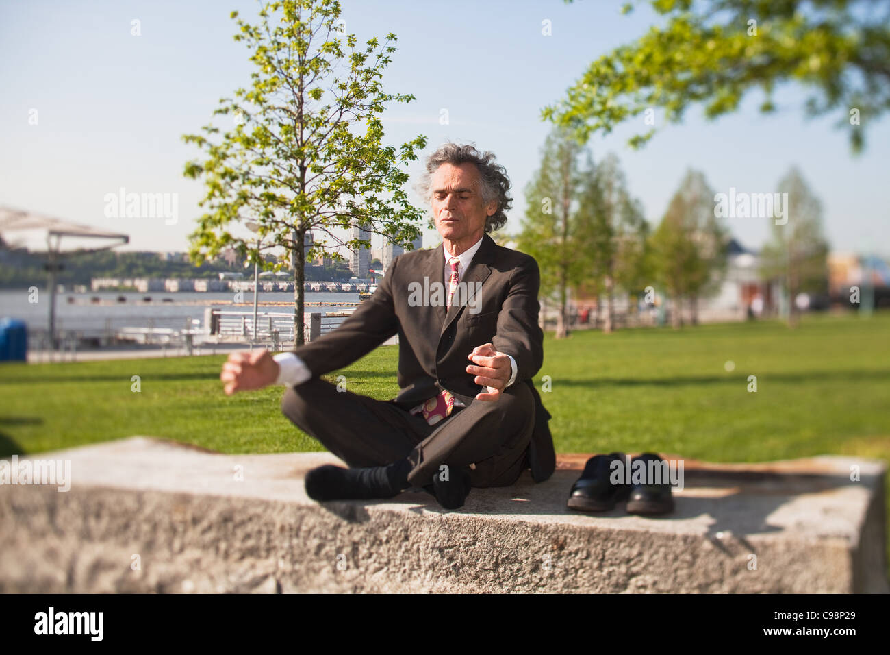 Ältere Mann mit Beine gekreuzt, meditieren park Stockfoto