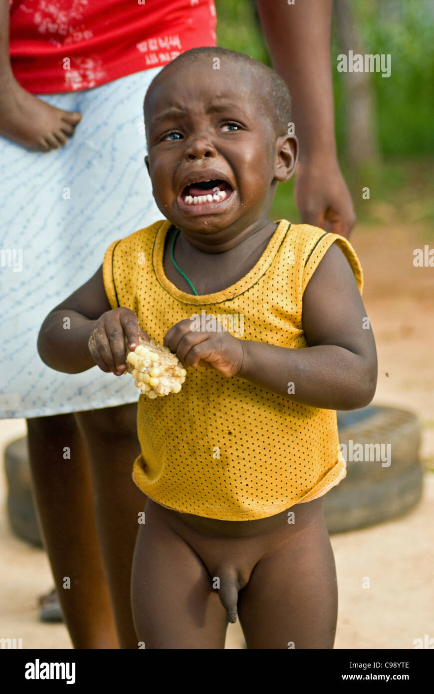 Ein simbabwischen jungen Weinen vor Hunger ist eine Hälfte gegessen "Mealie" gegeben. Stockfoto