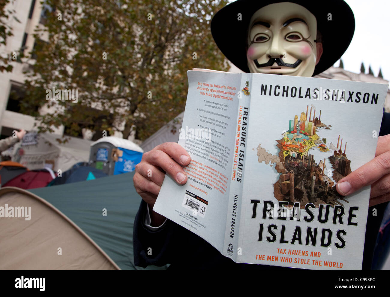 Aktivist mit Buch über Steueroasen in besetzen Camp, St. Pauls Cathedral, London Stockfoto