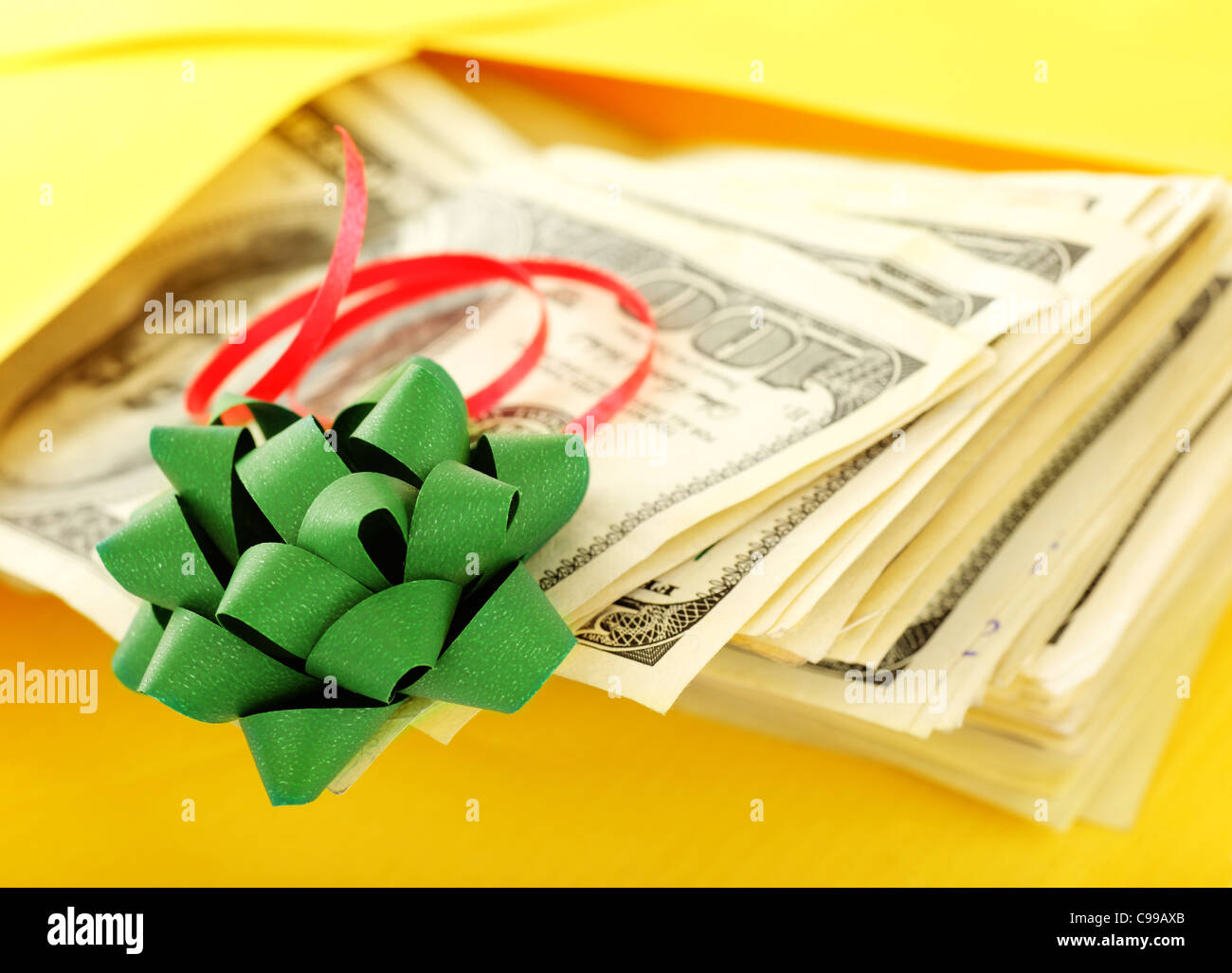 Geld als Geschenk mit grünen Bogen und gelben Umschlag Stockfoto