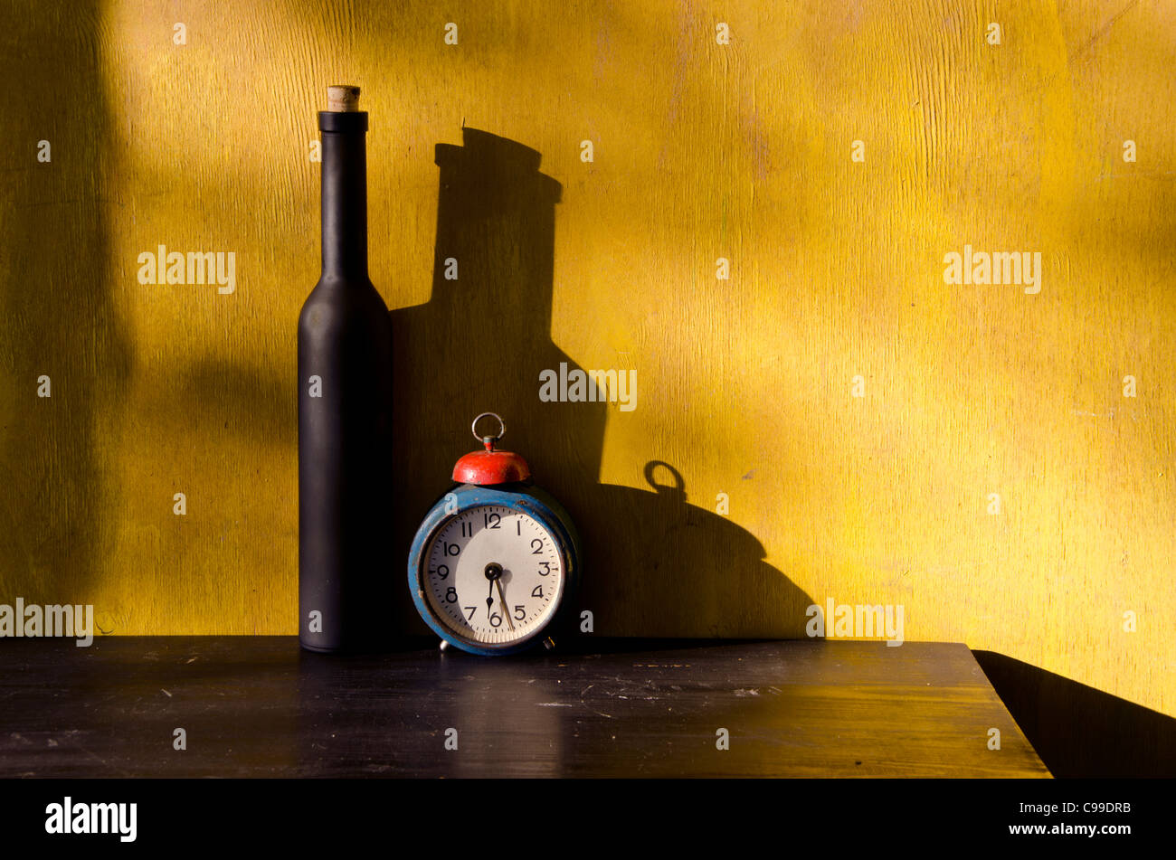 Still-Leben mit schwarzen Flasche und alte Uhr auf gelbem Hintergrund Stockfoto