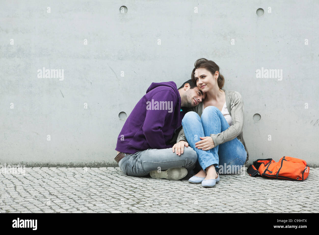 Deutschland, Berlin, paar, sitzen vor großen Wand auf Bürgersteig Stockfoto