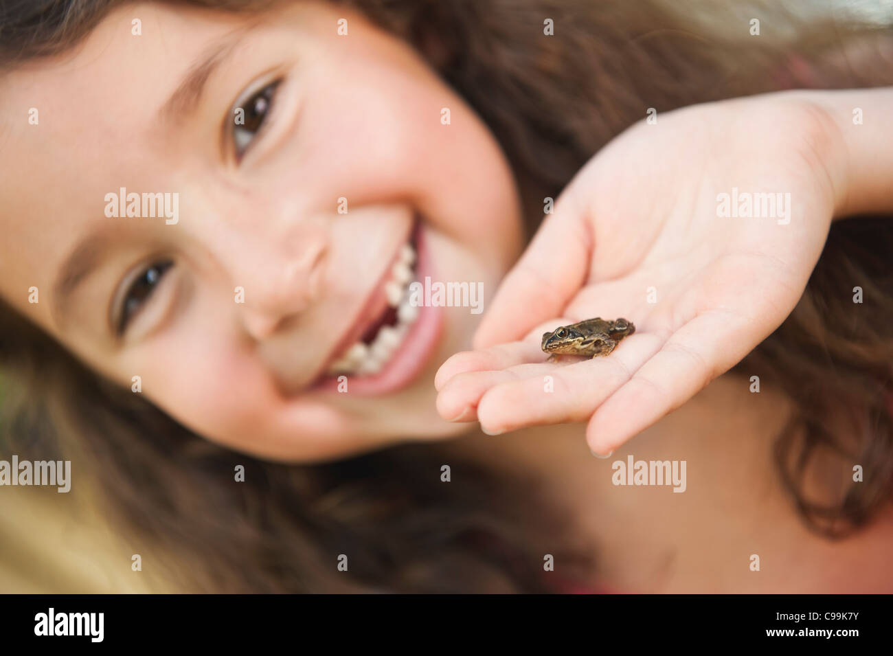 Deutschland, Bayern, menschliche Hand mit kleiner Frosch, Mädchen lächelnd im Hintergrund Stockfoto