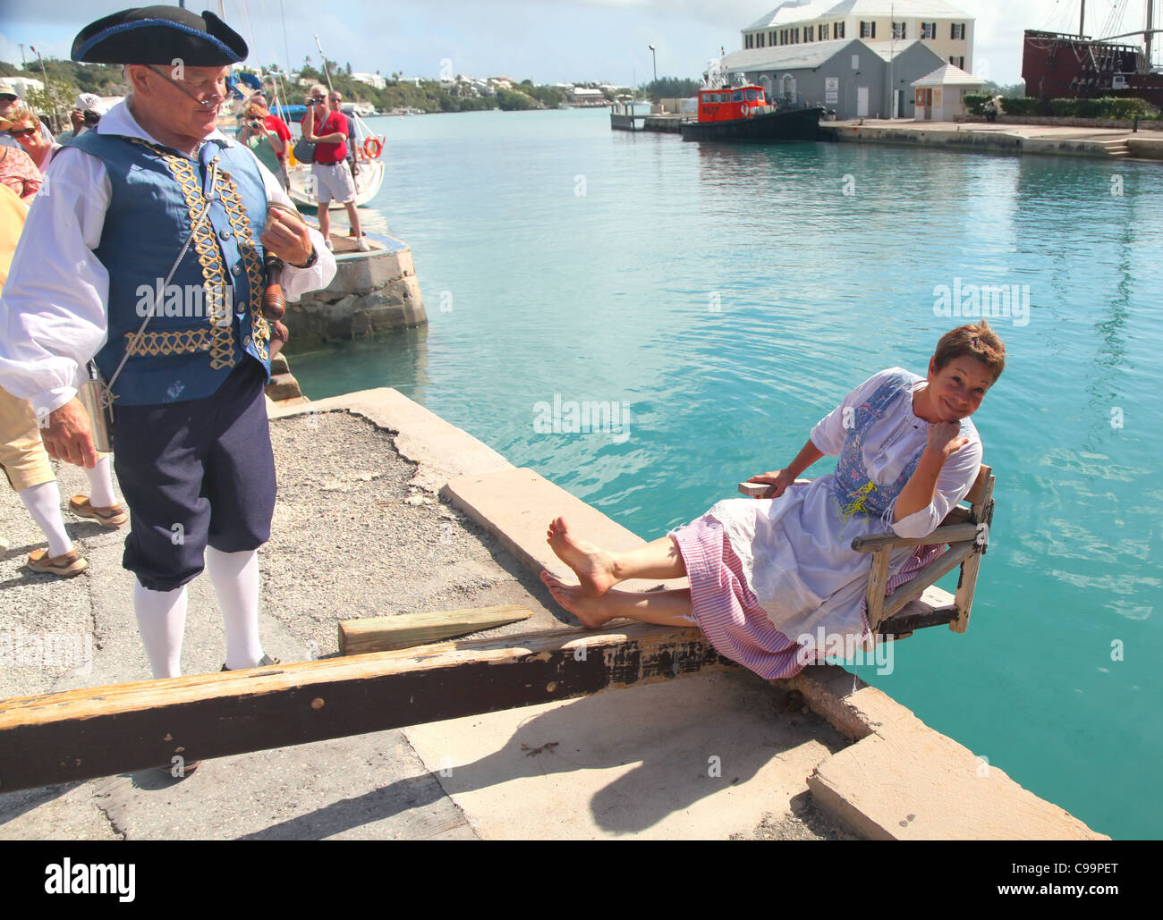 Eine Frau wird zu 'The Dunking Stuhl", als"Nag und Klatsch"in ein historisches Reenactment in St. Georges, Bermuda verurteilt. Stockfoto