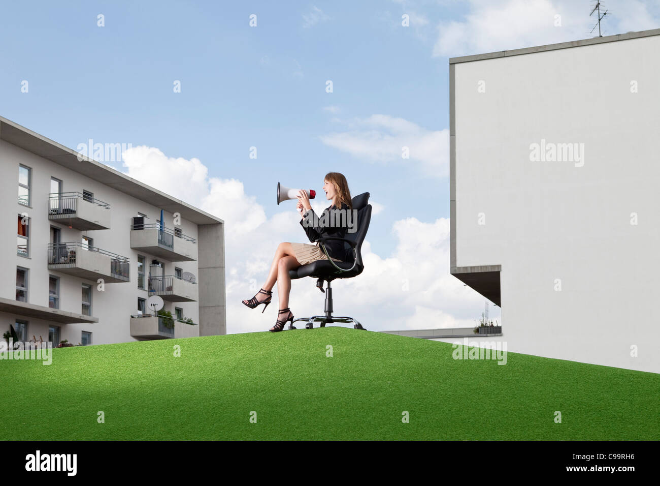 Deutschland, Bayern, München, Geschäftsfrau auf Bürostuhl sitzen und schreien durch maghaphone Stockfoto