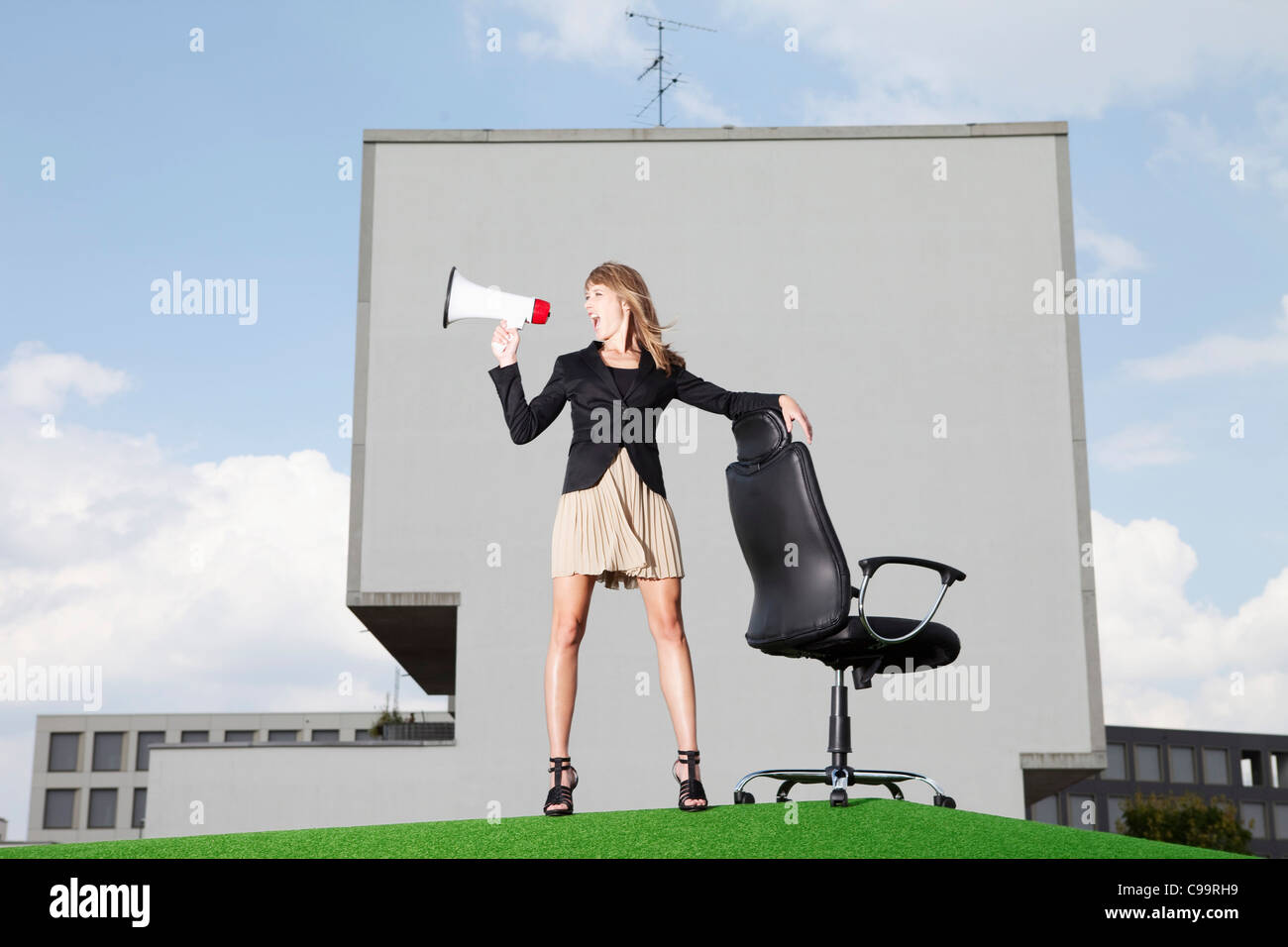 Deutschland, Bayern, München, Geschäftsfrau, die schreiend durch Meghaphone in Rasen Stockfoto