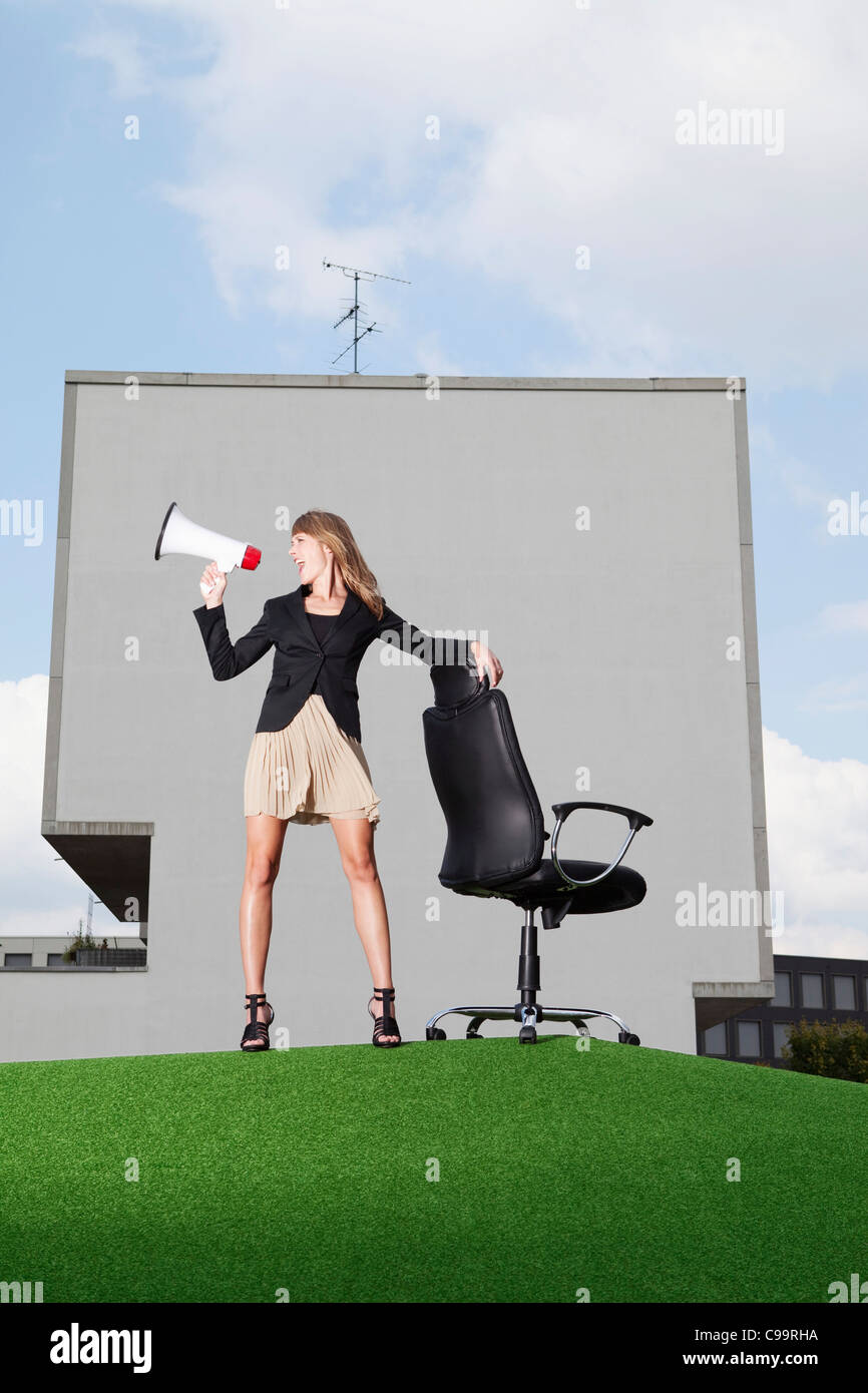 Deutschland, Bayern, München, Geschäftsfrau, die schreiend durch Meghaphone in Rasen Stockfoto