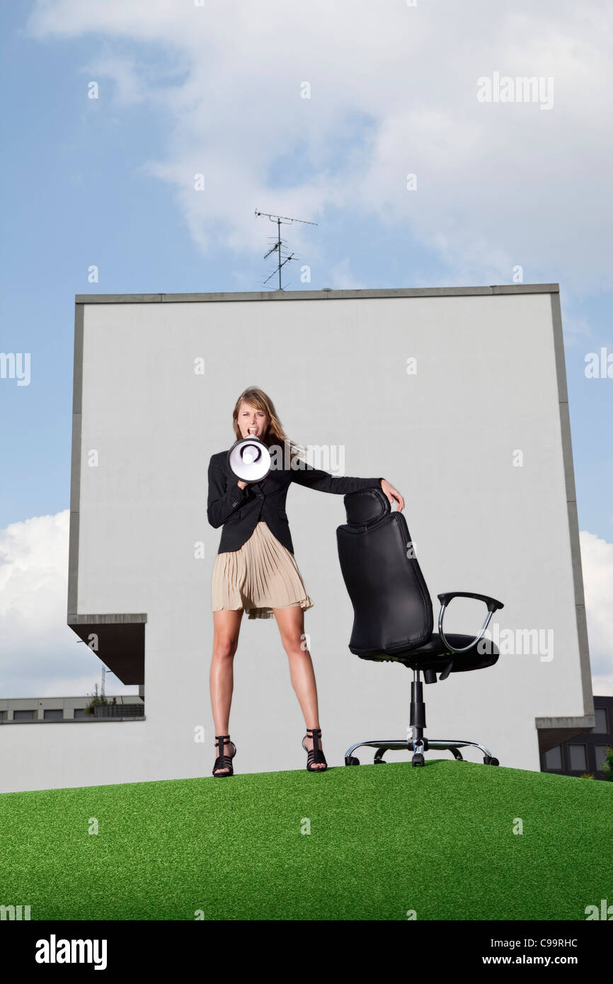 Deutschland, Bayern, München, Geschäftsfrau, die schreiend durch Meghaphone in Rasen Stockfoto