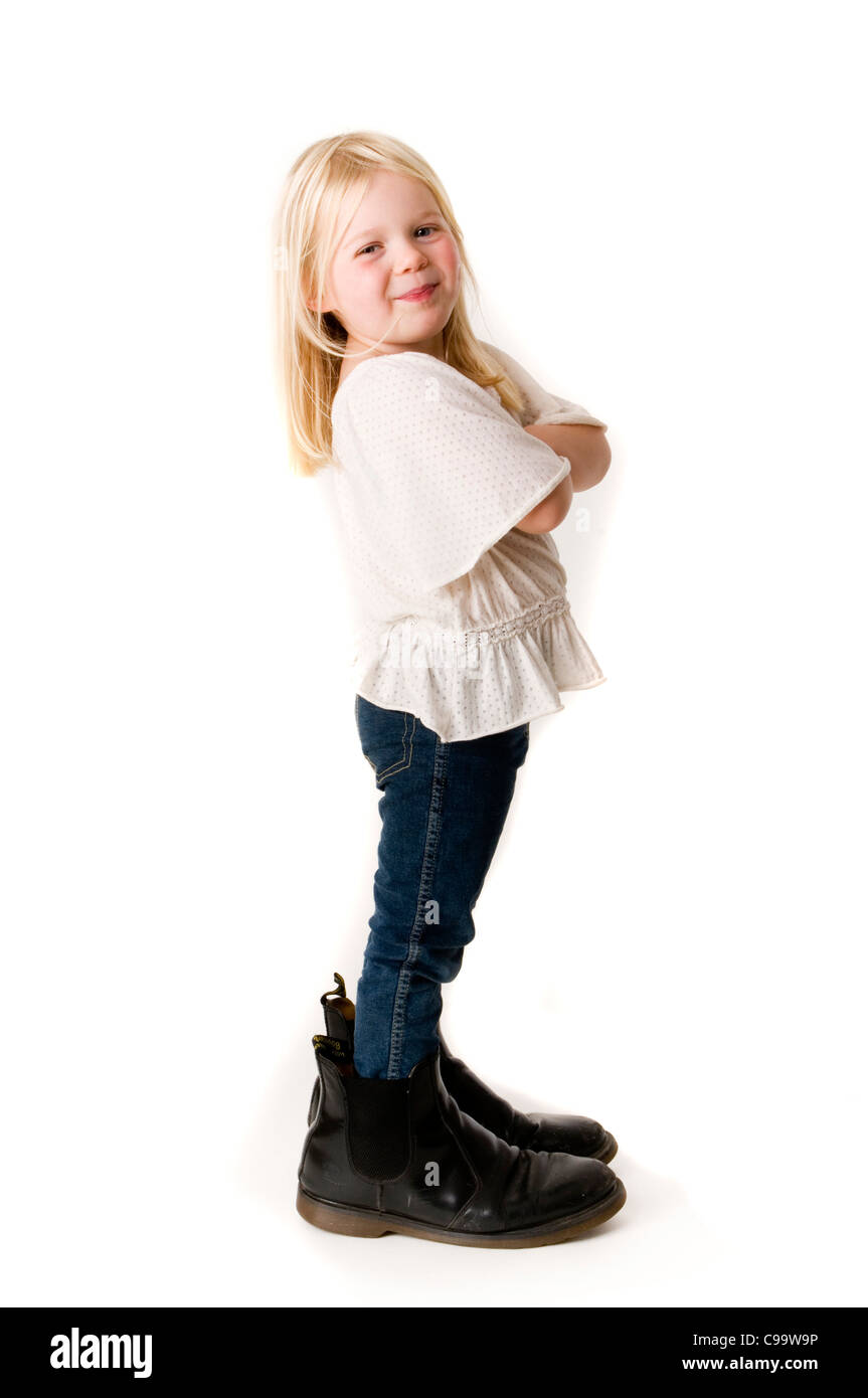 Bossy boots zu groß für Ihr Boot lustige Mädchen Kleinkind in große Fußstapfen versuchen Väter Stiefel auf Selbstvertrauen Wertschätzung zuversichtlich confid Stockfoto