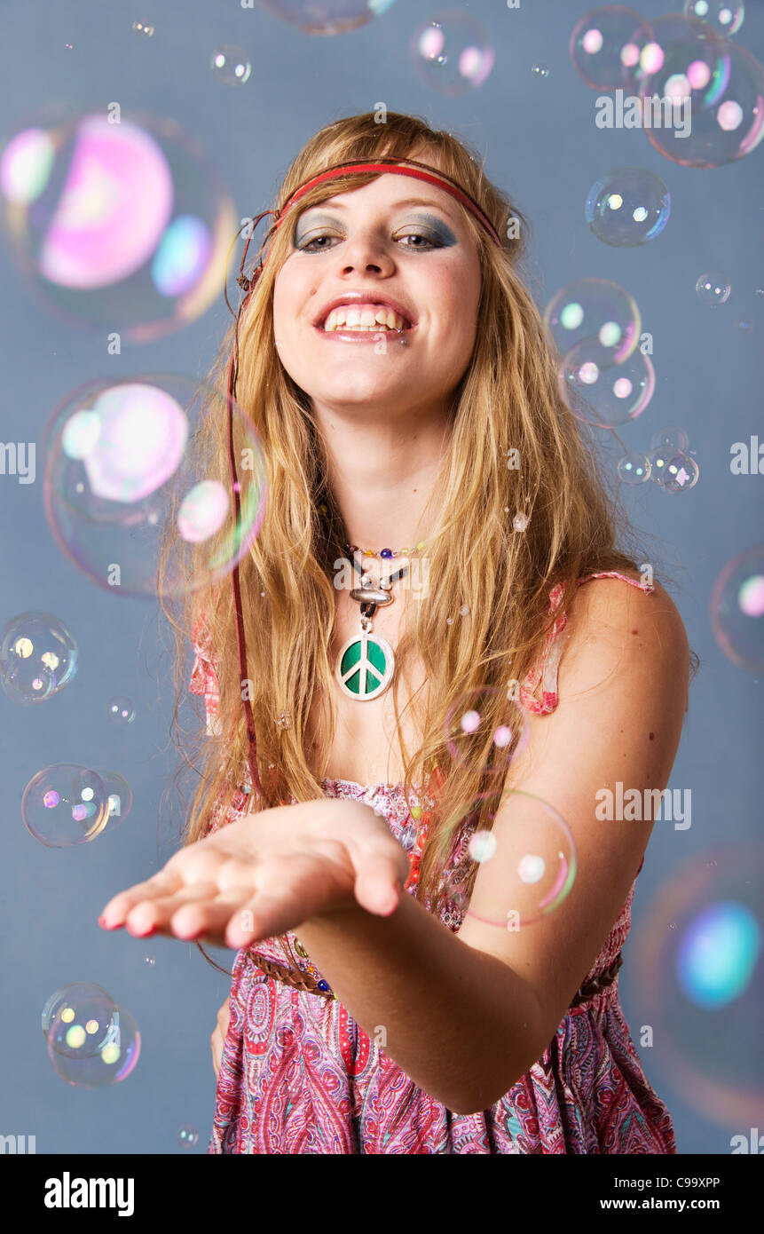 Jungen Hippie-Frau mit Luftblasen vor grauem Hintergrund, Lächeln Stockfoto