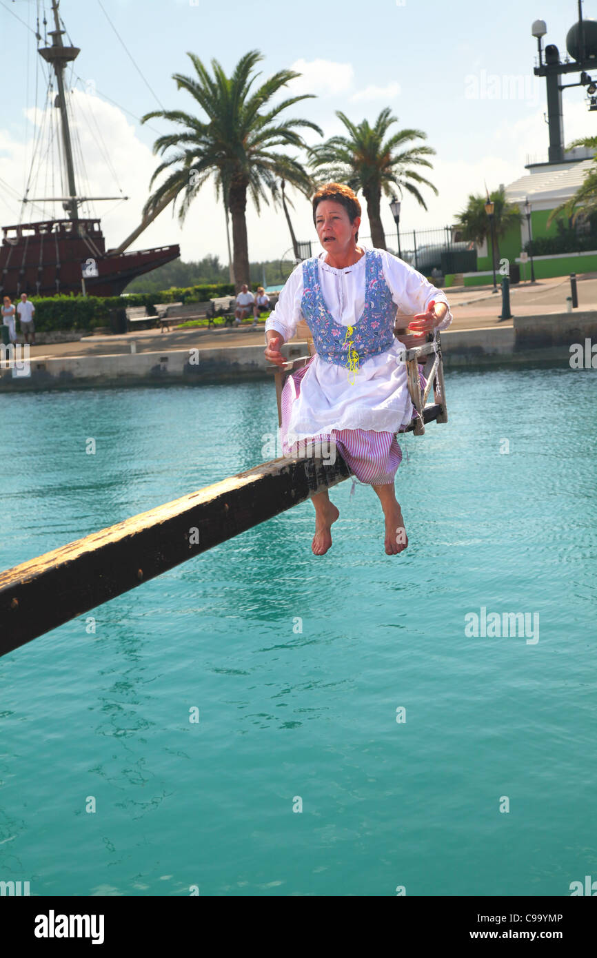 Eine Frau wird zu 'The Dunking Stuhl", als"Nag und Klatsch"in ein historisches Reenactment in St. Georges, Bermuda verurteilt. Stockfoto