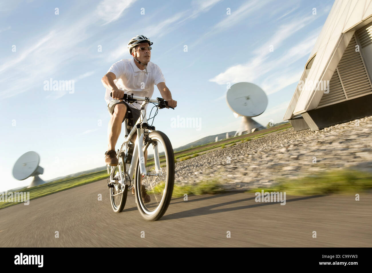 Deutschland, Bayern, Raisting, reifer Mann Reiten Fahrrad in der Nähe von Radiosender Stockfoto