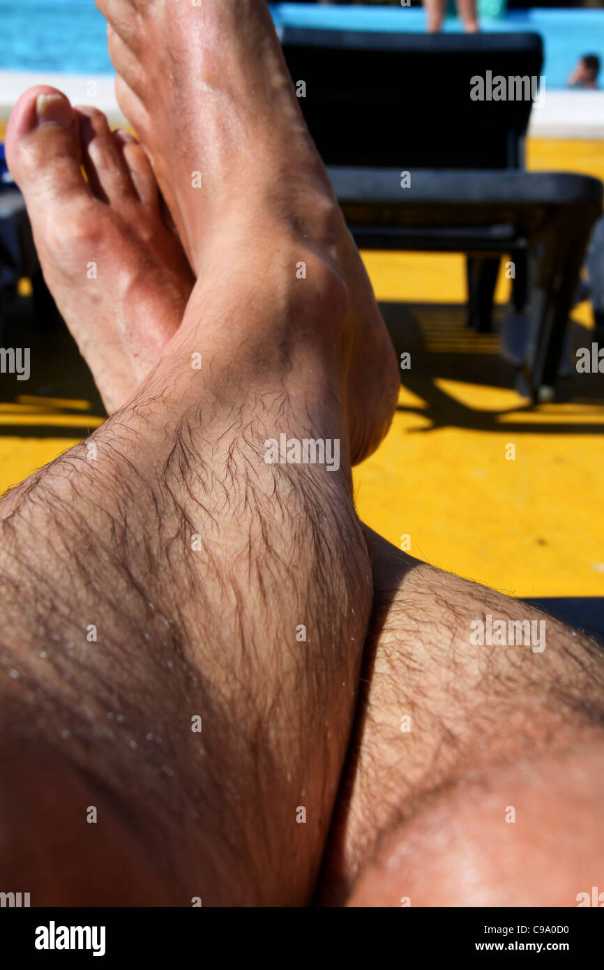 Mans Beine liegen auf der Sonnenbank Stockfoto