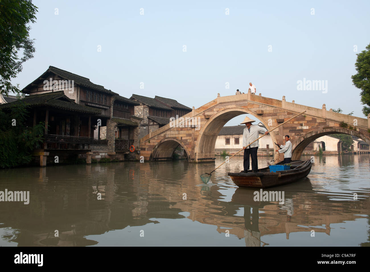 Boot im Fluss mit alten Dorf Gebäude in der Nähe des Flusses in Wuzhen Stadt, Provinz Zhejiang, China Stockfoto