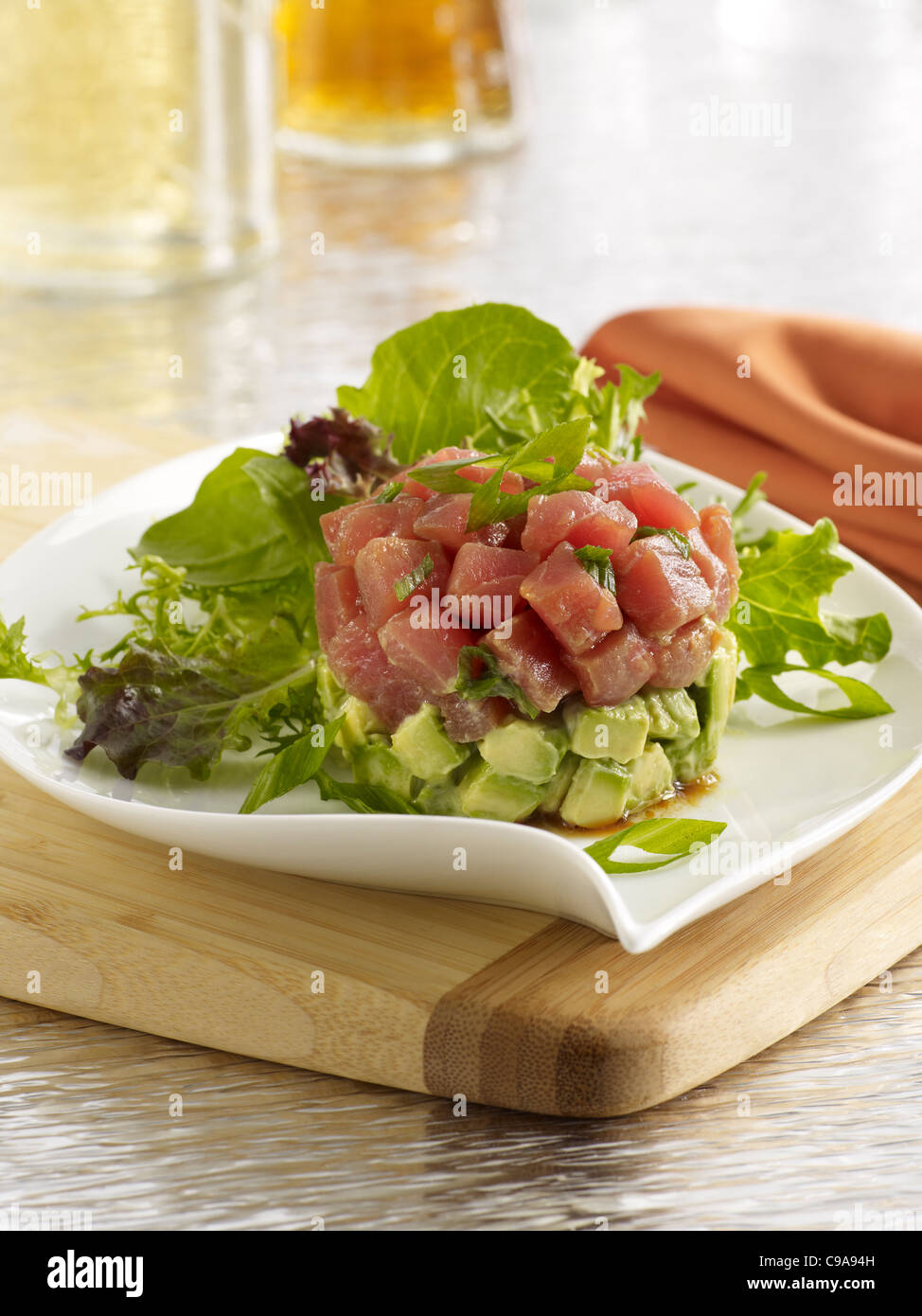 Thunfisch-Tartar-Salat mit Avocado auf einem weißen Teller und Blattgemüse Stockfoto