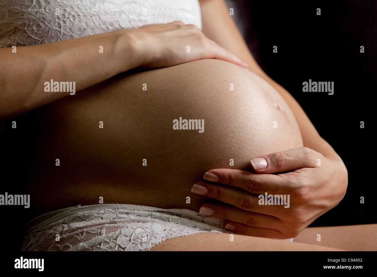 Frau die Hände acht Monate schwanger mit auf exponierten Bauch Stockfoto