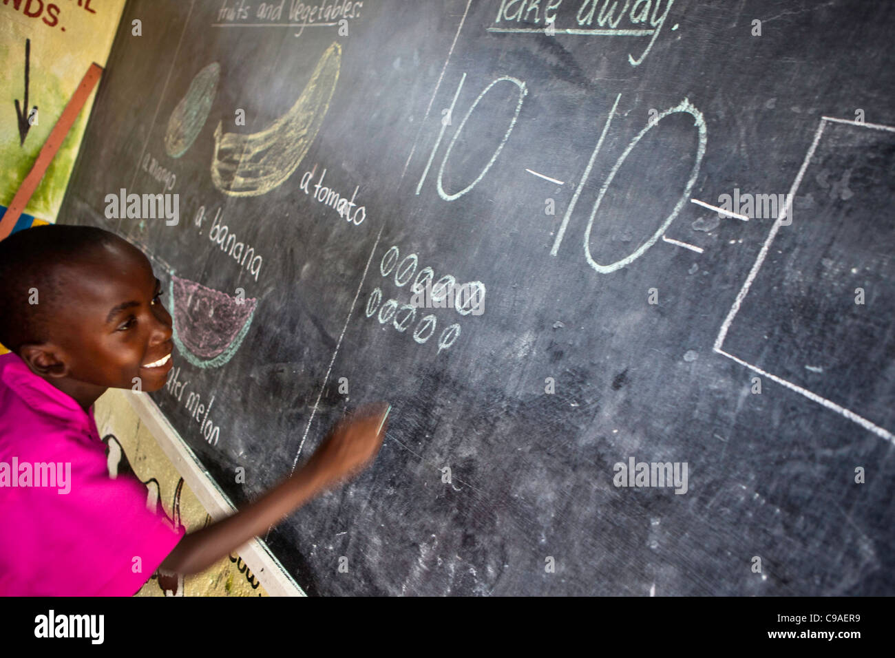 Ein Kind arbeitet eine Mathe-Frage an die Tafel während einer Schulklasse in der WEMA-Mitte. Mombasa, Kenia. Stockfoto