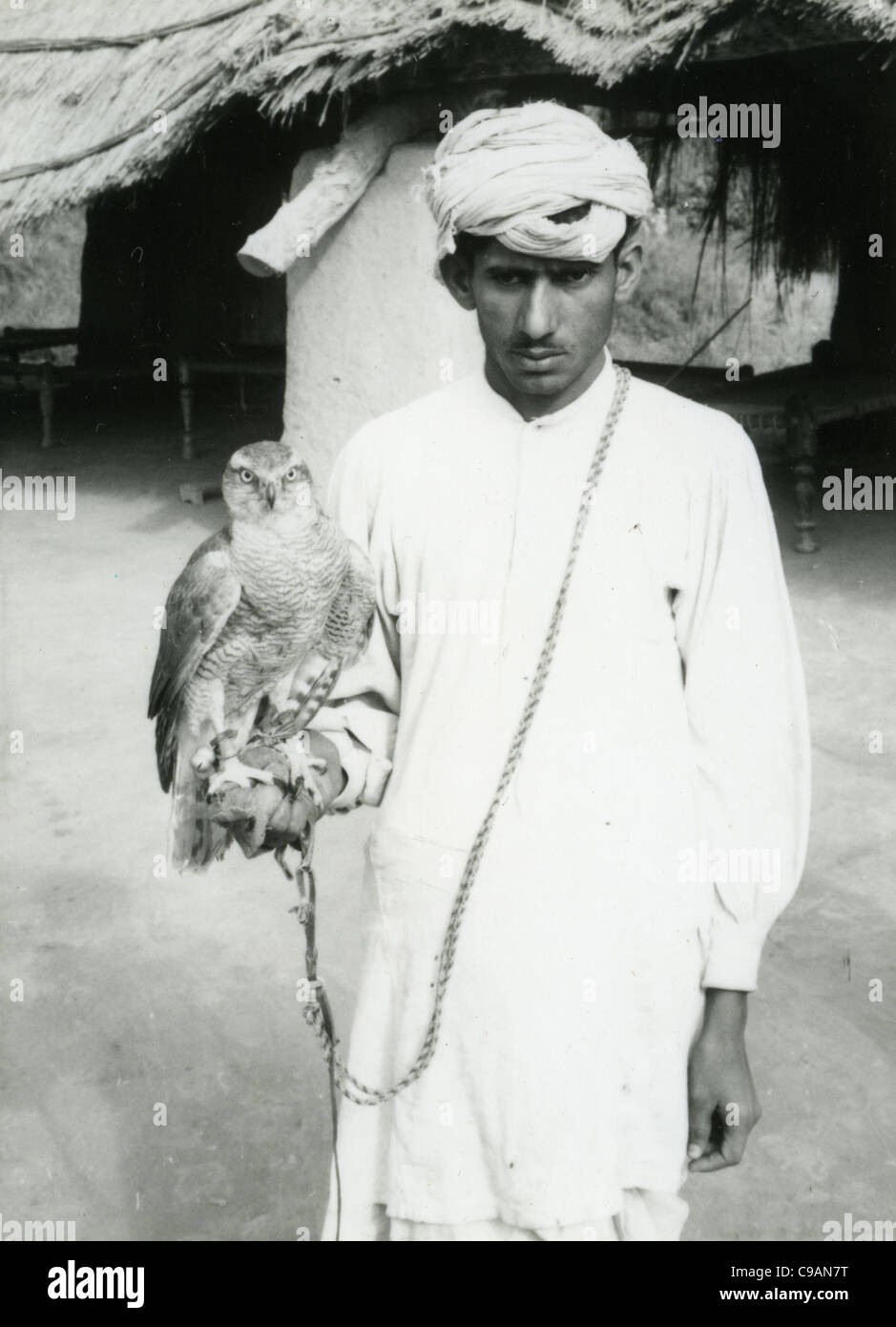 Junge im Turban und weiße Roben halten Falken in Pakistan in den frühen 1960er Jahren. Porträt und schwarz Stockfoto