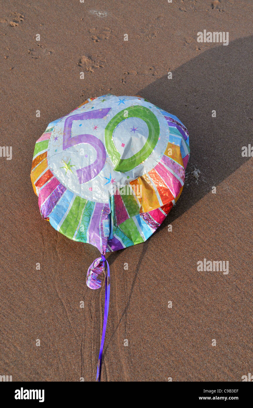 Ein halb deflationiert 50. Geburtstag Party Ballon am Strand verworfen liegt / Boden. Stockfoto