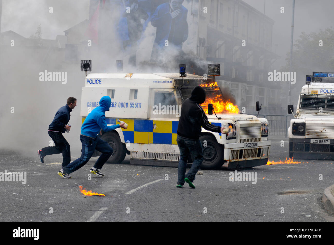 Maskierte nationalistische Jugendliche werfen Molotowcocktails auf PSNI Fahrzeuge während der Unruhen in Bogide, Londonderry. Stockfoto
