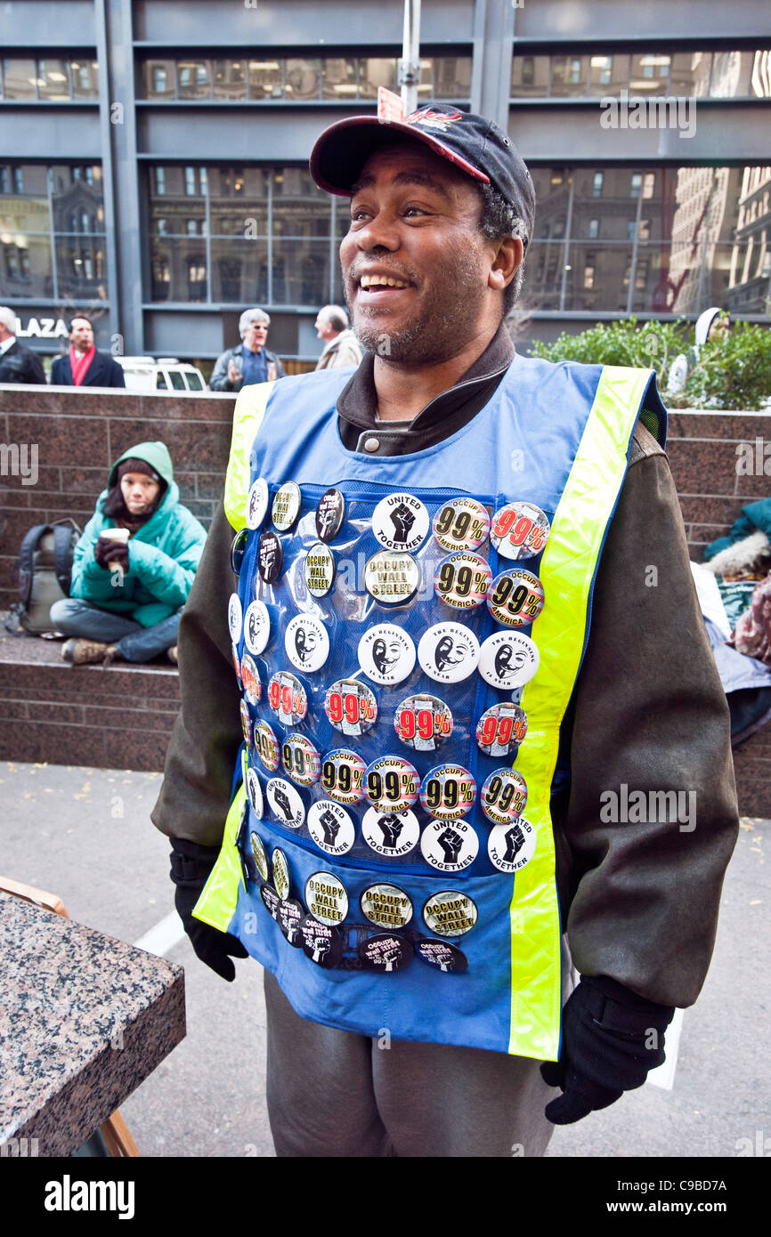 genialer schwarz Hersteller mit Weste bedeckt mit Occupy Wall Street-Tasten für den Verkauf an Bewegung Zuccotti Park 18. November 2011 profitieren Stockfoto