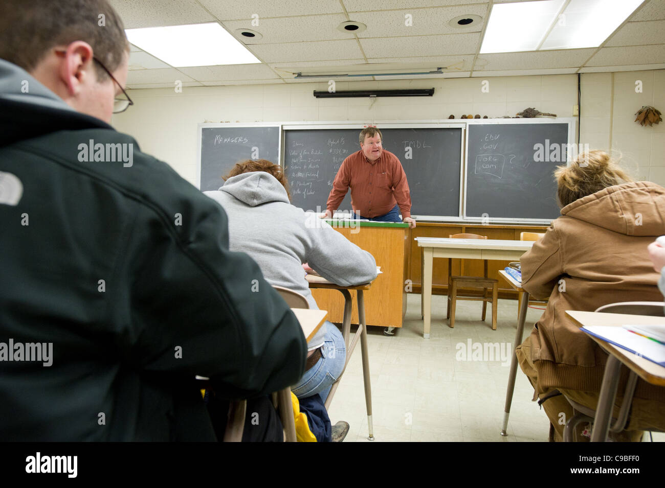Studenten an einem Schreibtisch und einem Lehrer an der Vorderseite ein Klassenzimmer Stockfoto