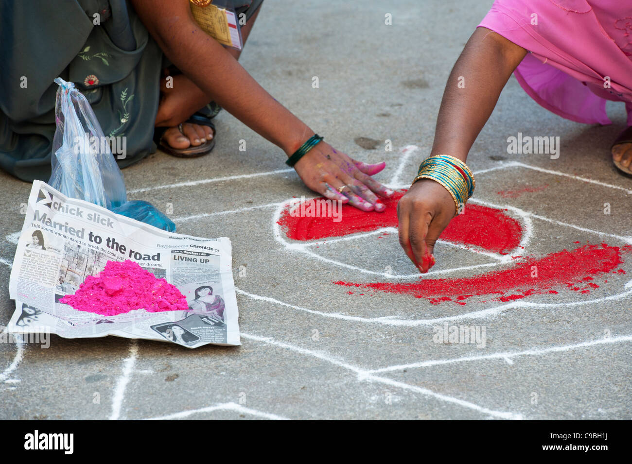 Indische Mädchen einen Rangoli Dasara festival Design in einem indischen Straße. Puttaparthi, Andhra Pradesh, Indien Stockfoto