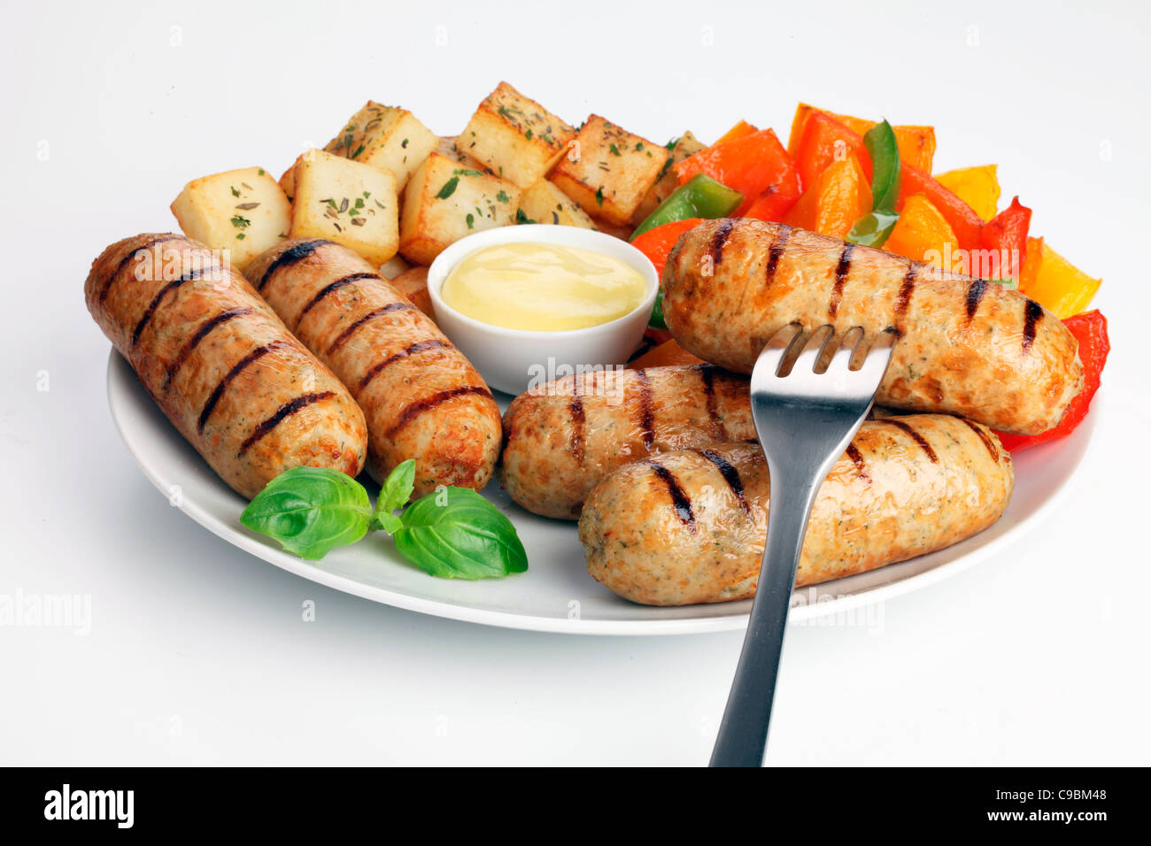 HÜHNCHEN WÜRSTCHEN BRATEN KARTOFFELN Stockfoto