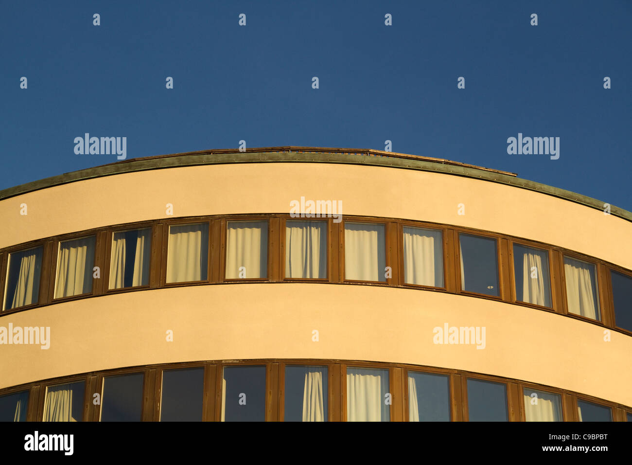 Enger Foto von geschwungenen Gebäude mit Fenstern und blauem Himmel bei Sonnenuntergang Stockfoto