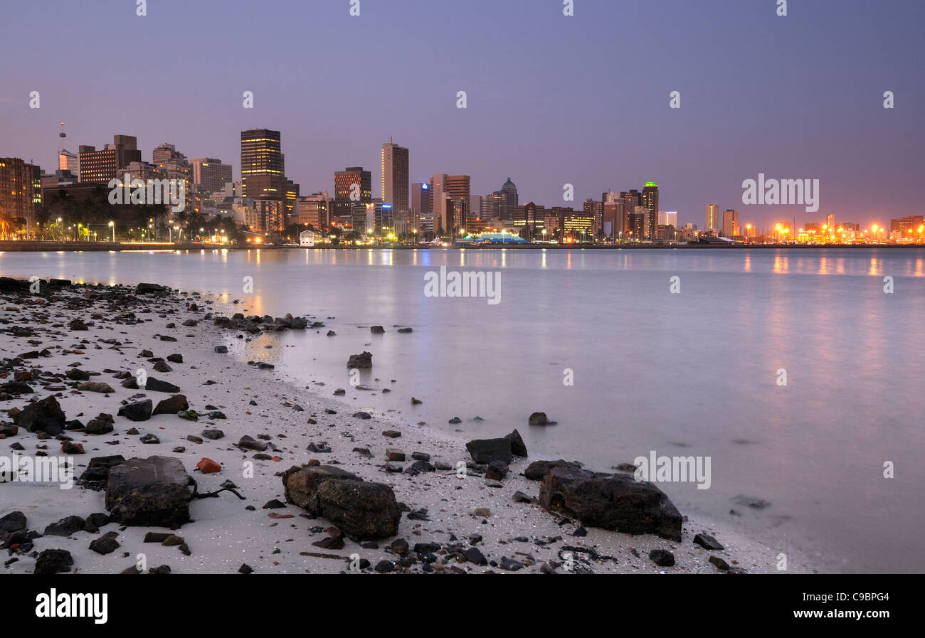 Lichter der Stadt in der Dämmerung mit Schutt übersäten Strand im Vordergrund, Durban, Kwazulu Natal, Südafrika Stockfoto