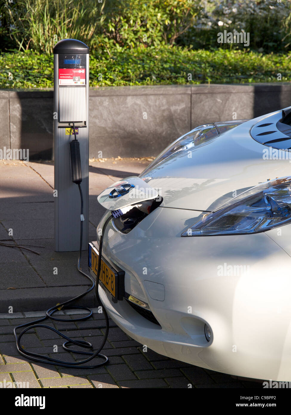 Elektroauto Nissan Leaf angeschlossen und geladen in Amsterdam, Niederlande Stockfoto