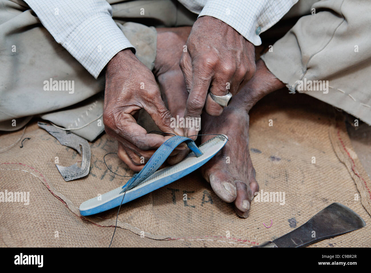 Mann, Reparatur von Schuhen auf der Straße im Dorf Sarod, Bundesstaat Gujarat, Indien. Stockfoto