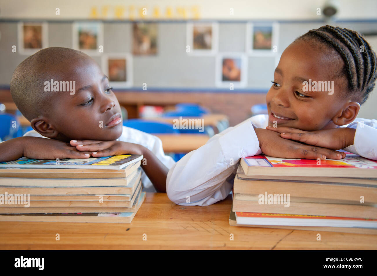Jungen und Mädchen stützte sich auf Bücher am Schreibtisch im Klassenzimmer, Johannesburg, Provinz Gauteng, Südafrika Stockfoto