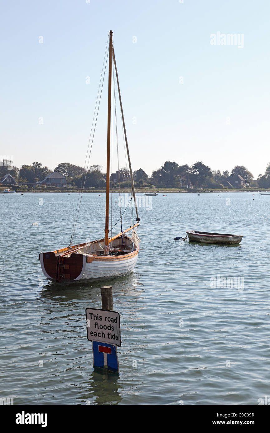 Segelboot und Straße Überschwemmungen jeder Tide Zeichen Bosham Hafen Chichester West Sussex Stockfoto