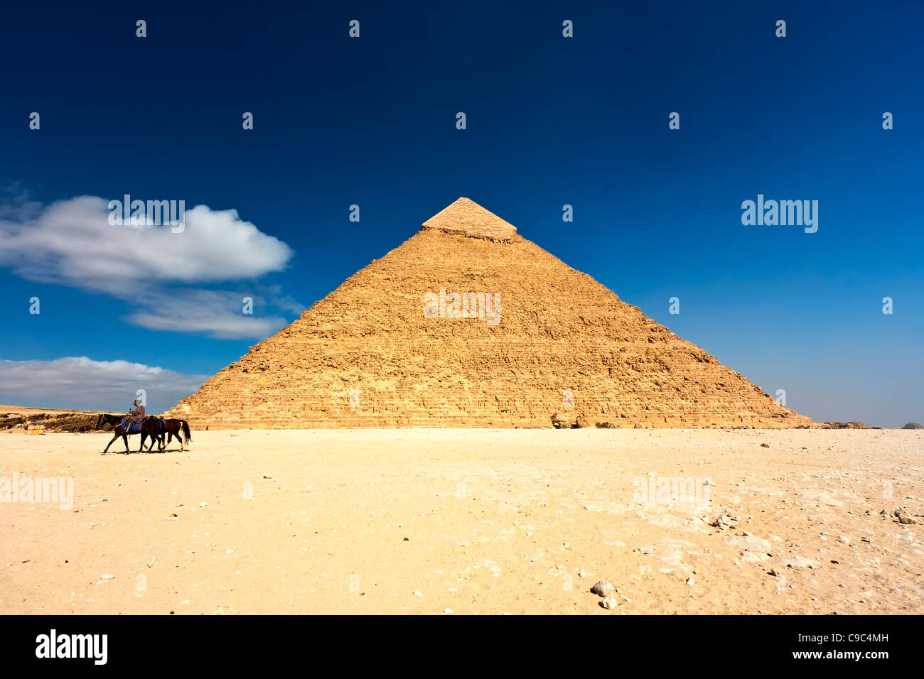 Ein Mann auf einem Pferd reitet durch die Wüste vorbei an der Pyramide des Chephren in Gizeh Neropolis Stockfoto