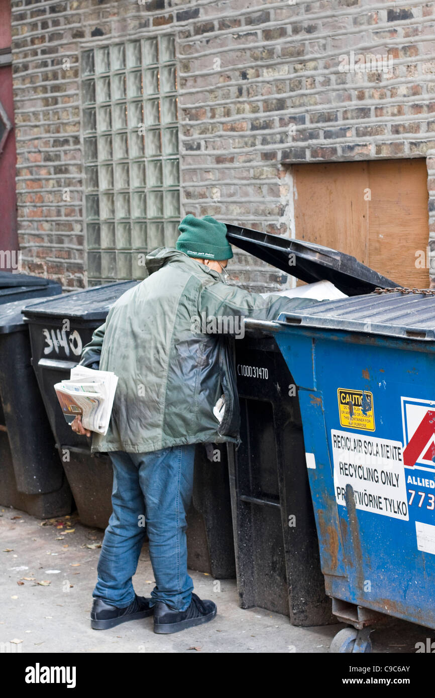 Ein Mann schaut durch ein Papierkorb in einer Gasse in Chicago. Stockfoto