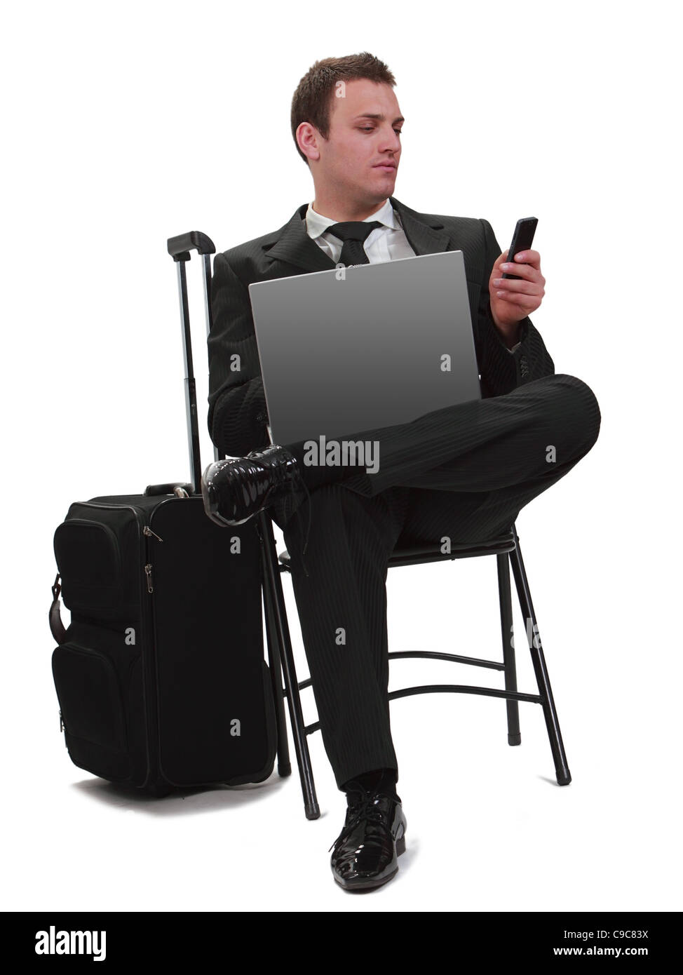 Junger Geschäftsmann eine telefonische Nachricht zu lesen, während sie neben ihren Koffer mit seinem Laptop sitzt. Stockfoto