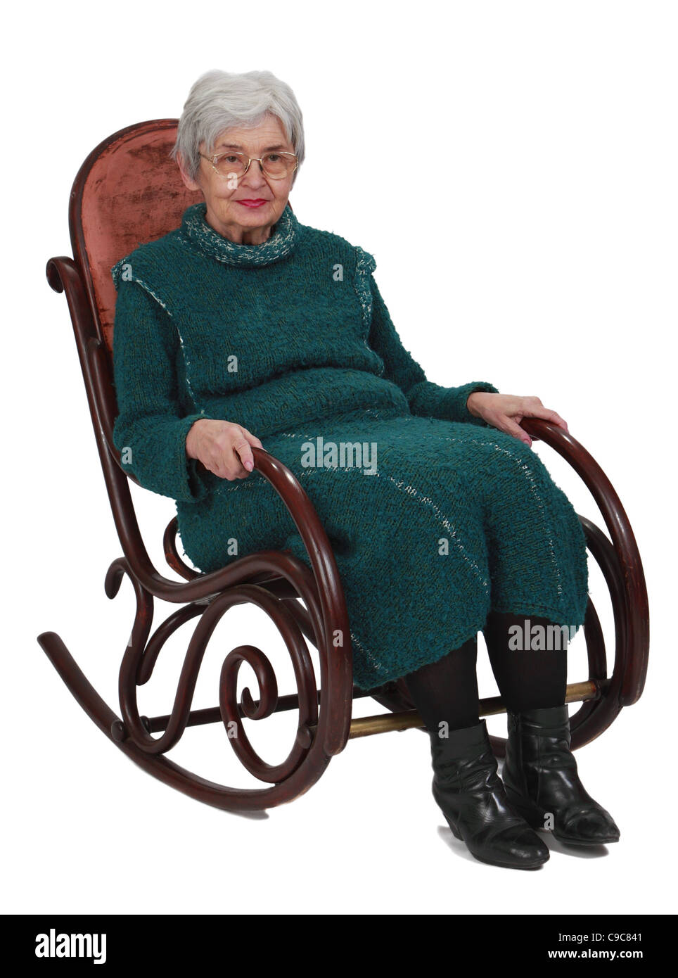 Alte Frau sitzt auf einem hölzernen Schaukelstuhl vor einem weißen Hintergrund isoliert. Stockfoto