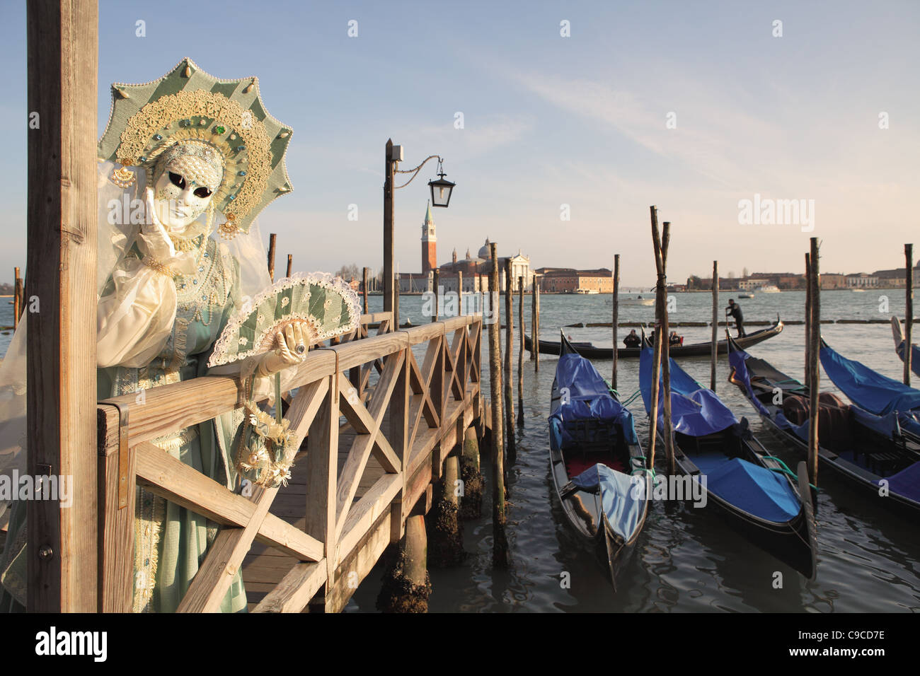 Unbekannte Teilnehmer mit traditionellen Maske und Kostüm gegen Canal grande und San Giorgio Maggiore Kirche in Venedig, Italien. Stockfoto