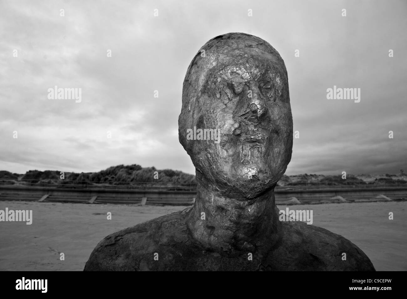 Crosby Strand nahe Liverpool, Merseyside, England, mit korrodierten Figur aus Gormleyss Arbeit "Woanders" Stockfoto