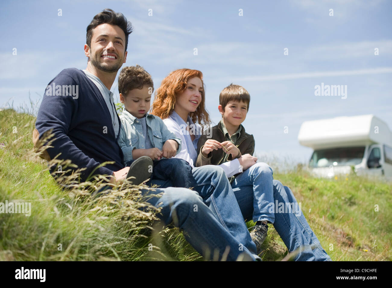 Eltern und Jugendliche Jungs sitzen auf der Wiese Stockfoto