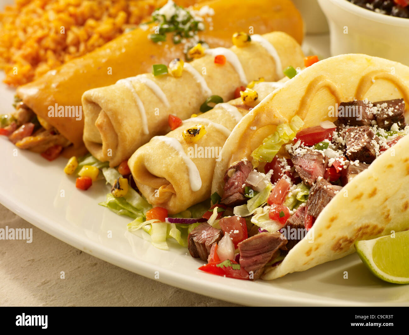 Ein Rindfleisch Taco, zwei Chimichangas und eine Enchilada Sauce bedeckt und serviert mit spanischen Reis und schwarze Bohnen Stockfoto