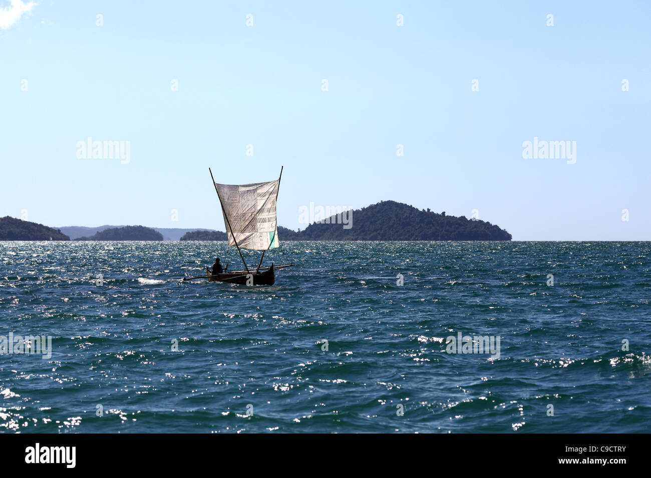 Ein Fischer an der Spitze seiner Segeln Ausleger Einbaum-Kanu mit einem behelfsmäßigen Segel aus Mamoko, Nordwesten Madagaskars. Stockfoto