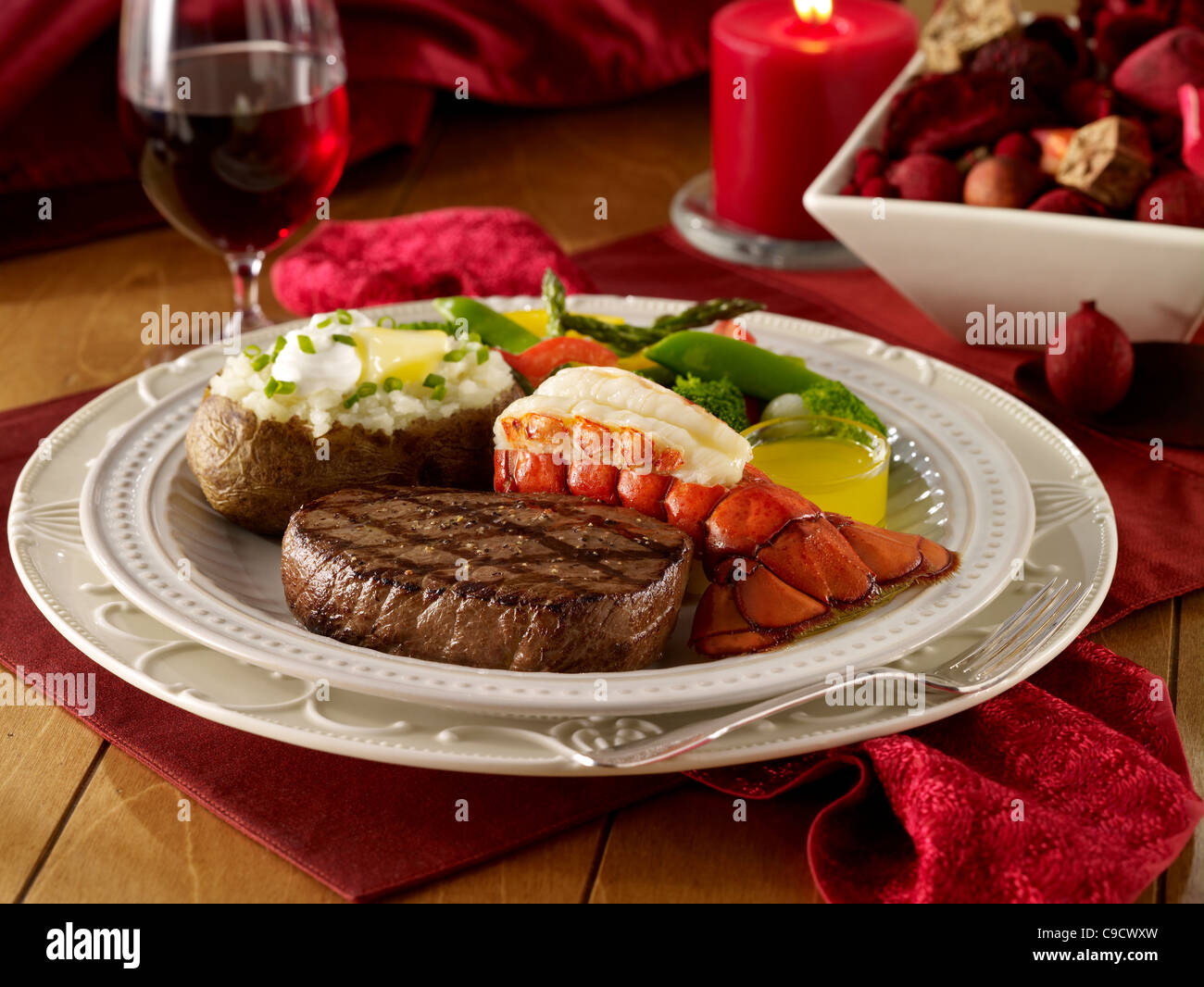 Steak und Hummer Abendessen mit einer geladenen gebackene Kartoffel, Gemüse und ein Glas Rotwein Stockfoto