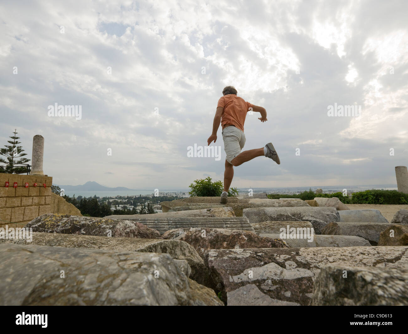 Tunesien, Karthago, Mann springt zwischen den gefallenen Spalten in Carthage Ruine Stockfoto