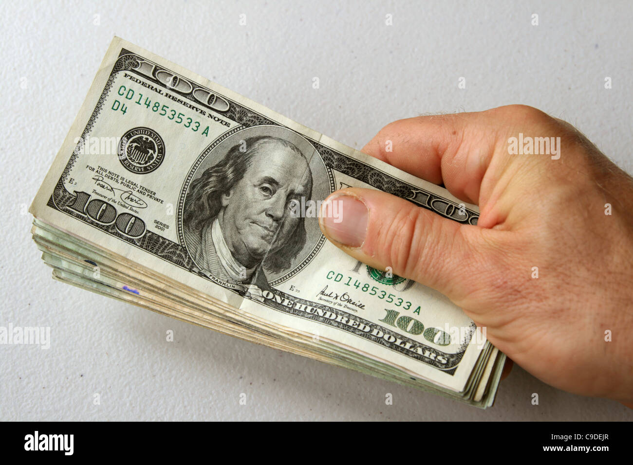 Des Mannes Hand, die Stapel von US-Geld mit 100 Dollar-Schein an der Spitze Stockfoto