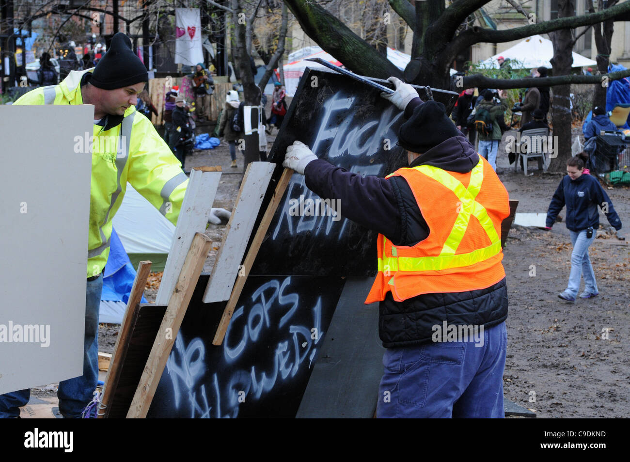 23. November 2011, kamen Toronto Polizei in großer Zahl am frühen Morgen, beginnen mit dem vertreiben der besetzen Toronto-Zelt-Camp vom St. James Park.  Hier gelten Stadtarbeiter Demontage ein profaner Schild neben dem Musikpavillon. Stockfoto